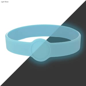 A light blue silicone wristband with a circular imprint area and a glowing effect.