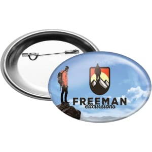 An oval button badge featuring a mountainous design with a figure, in blue, black, and white colours.