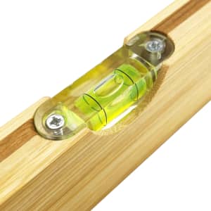 A drink bottle opener leveller made of bamboo, featuring a green spirit level. It has a simple, natural design.