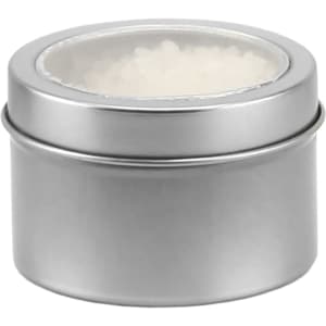 A silver tin containing white bath salts, featuring a clear lid. The tin has a smooth finish and a circular shape.