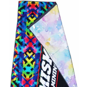 A beach towel featuring a vibrant, multi-coloured geometric pattern with a soft, pastel-lined underside and a logo.