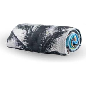 A rolled beach towel featuring a palm leaf pattern in black, white, and blue colours, with a logo present.