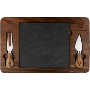 A slate cheeseboard with a wooden border and two cheese knives, featuring a logo. The board has a rectangular shape.