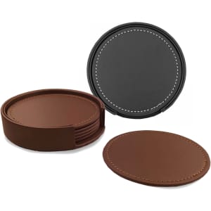 A set of six leather coasters in brown and black, stored in a round holder with stitching detail.
