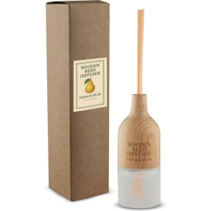 A wooden reed diffuser with a cylindrical base and two reeds, packaged in a brown box. The diffuser has a light colour.
