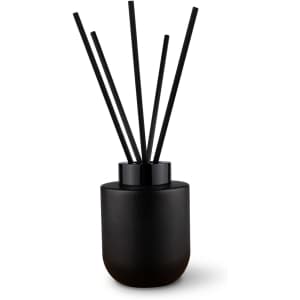 A black botanical reed diffuser with five black reeds, designed for fragrance dispersal.