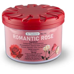 A round container of air freshener with a pink label featuring red and white roses and a red lid.