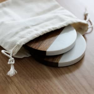 A drink bottle opener and coasters in a natural-coloured fabric bag, featuring wood and marble textures.