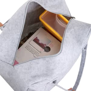 A grey felt travel bag with an open top displaying a yellow container and a book inside.