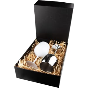 A stainless steel wine glass with a black box and shredded paper filling, featuring a white wine glass alongside.