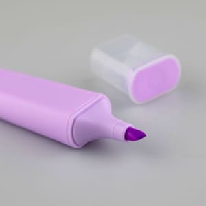 A purple highlighter with a chisel tip and a translucent cap placed nearby. The product has a smooth, sleek design.