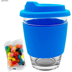 A glass coffee cup with a light blue silicone lid and sleeve, accompanied by a pack of colourful jelly beans.