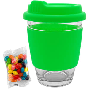 A green Carlo glass coffee cup with a silicone sleeve, accompanied by a bag of colourful jelly beans.