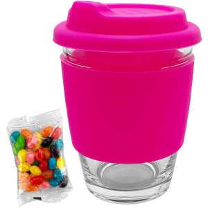 A pink silicone-covered glass coffee cup with a lid, accompanied by a bag of colourful jelly beans.