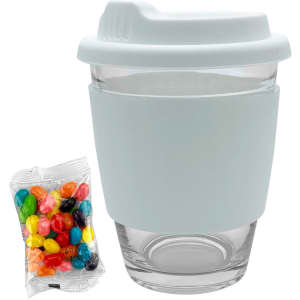 A Carlo glass coffee cup with a white silicone sleeve, accompanied by a pack of multicoloured jelly beans.