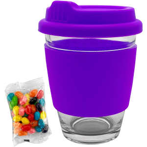 A purple glass coffee cup with a silicone lid and sleeve, accompanied by a packet of colourful jelly beans.