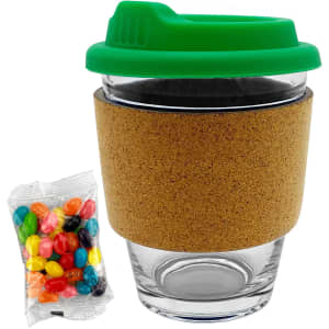 A glass coffee cup with a green lid and cork band, accompanied by a pack of colourful jelly beans.
