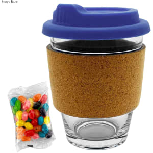 A glass coffee cup with a navy blue lid and cork band, accompanied by a pack of colourful jelly beans.