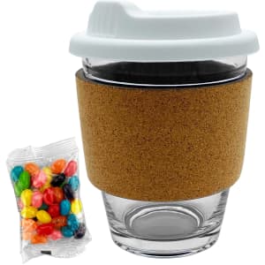 A glass coffee cup with a white lid and cork band, alongside a packet of colourful jelly beans.