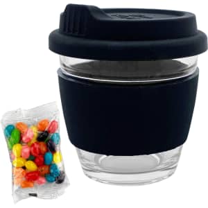 A glass coffee cup with a black silicone sleeve, accompanied by a packet of colourful jelly beans.