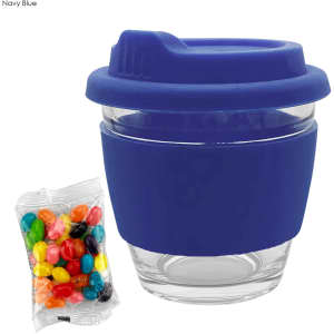 A reusable coffee cup with a navy blue silicone sleeve and lid, accompanied by a packet of colourful jelly beans.
