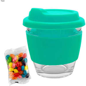 A drink cup made of glass with a teal silicone sleeve and lid, accompanied by a bag of colourful jelly beans.