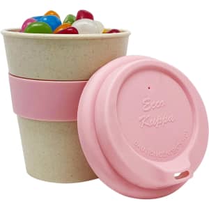 A bamboo cup featuring a pink silicone band and lid, filled with colourful jelly beans. The cup has a logo.