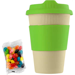A reusable 12oz bamboo coffee cup in cream with a bright green lid and sleeve, accompanied by a pack of colourful jelly beans.