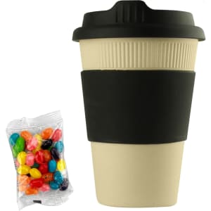 A reusable 12oz bamboo coffee cup in cream with a black sleeve, accompanied by a bag of colourful jelly beans.