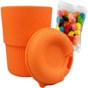 A reusable coffee cup in vibrant orange silicone, accompanied by a bag of colourful jelly beans.
