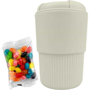 A reusable coffee cup in light beige, accompanied by a bag of colourful jelly beans. The cup features a logo.