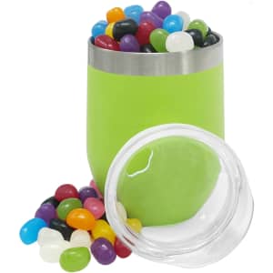 A green coffee cup filled with colourful jelly beans, next to a clear jar containing more jelly beans.