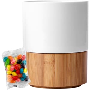 A white ceramic mug with a bamboo base alongside a packet of colourful jelly beans.