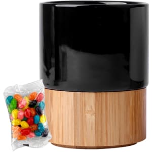 A black ceramic mug with a bamboo base, accompanied by a packet of colourful jelly beans.
