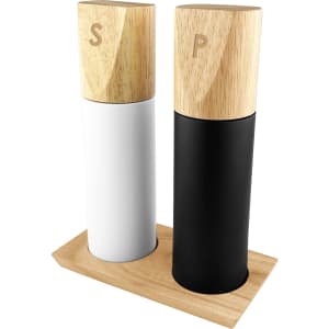 A salt and pepper grinder set with white and black ceramic bodies and wooden tops, displayed on a wooden base.