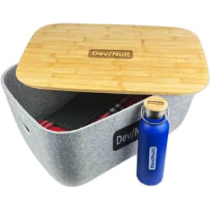 A grey storage tub with a bamboo lid and a blue drink bottle. The tub contains a patterned blanket.