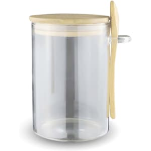 A clear glass container with a bamboo lid and spoon, designed for storing overnight oats.