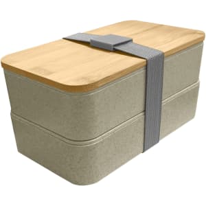 A wheat straw lunch box pack in a light beige colour, featuring a bamboo lid and a grey strap.