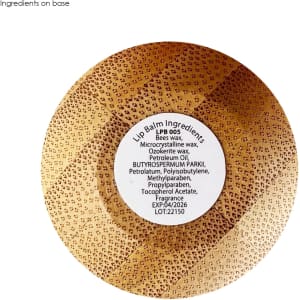 A bamboo-styled lip balm ball with a circular base, featuring a label listing ingredients.