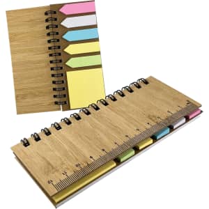 A bamboo sticky note holder with yellow, pink, and blue sticky notes and a ruler along one edge. It features a spiral binding.