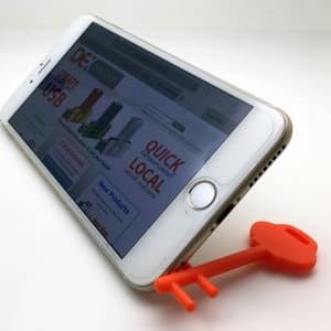 An orange mobile key stand supports a smartphone at an angle, displaying its screen.