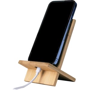 A bamboo phone holder in natural wood finish, supporting a smartphone with a charging cable connected.