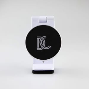 A white mobile phone stand with a black circular base featuring a logo. The design is sleek and modern.