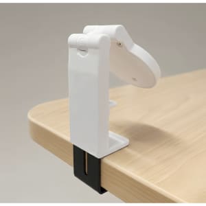 A white mobile phone stand clamps onto a wooden surface, featuring an adjustable holder for the device.