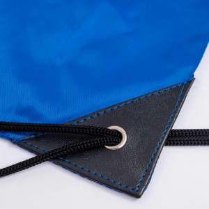 A blue nylon backsack featuring a black leather base and drawstring closure with metal eyelets.
