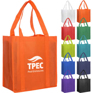 An orange non-woven shopping bag with two handles and a logo, surrounded by bags in various colours.