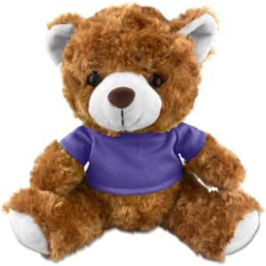 A brown teddy bear plush toy wearing a purple shirt, with soft fur and a friendly expression. It has a logo on the shirt.