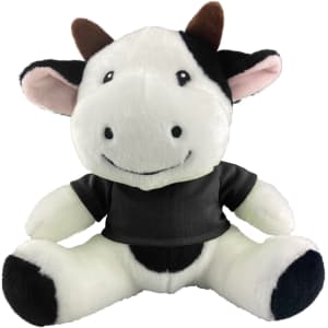 A plush cow toy in black and white with a smiling face and a black shirt, featuring a small logo.