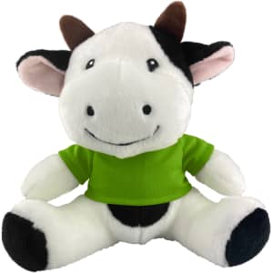 A plush cow toy with black and white fur, wearing a bright green shirt, sitting with a cheerful expression.