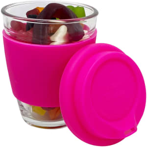 A pink reusable coffee cup holds a mix of jelly sweets, featuring a glass cup with a silicone sleeve.